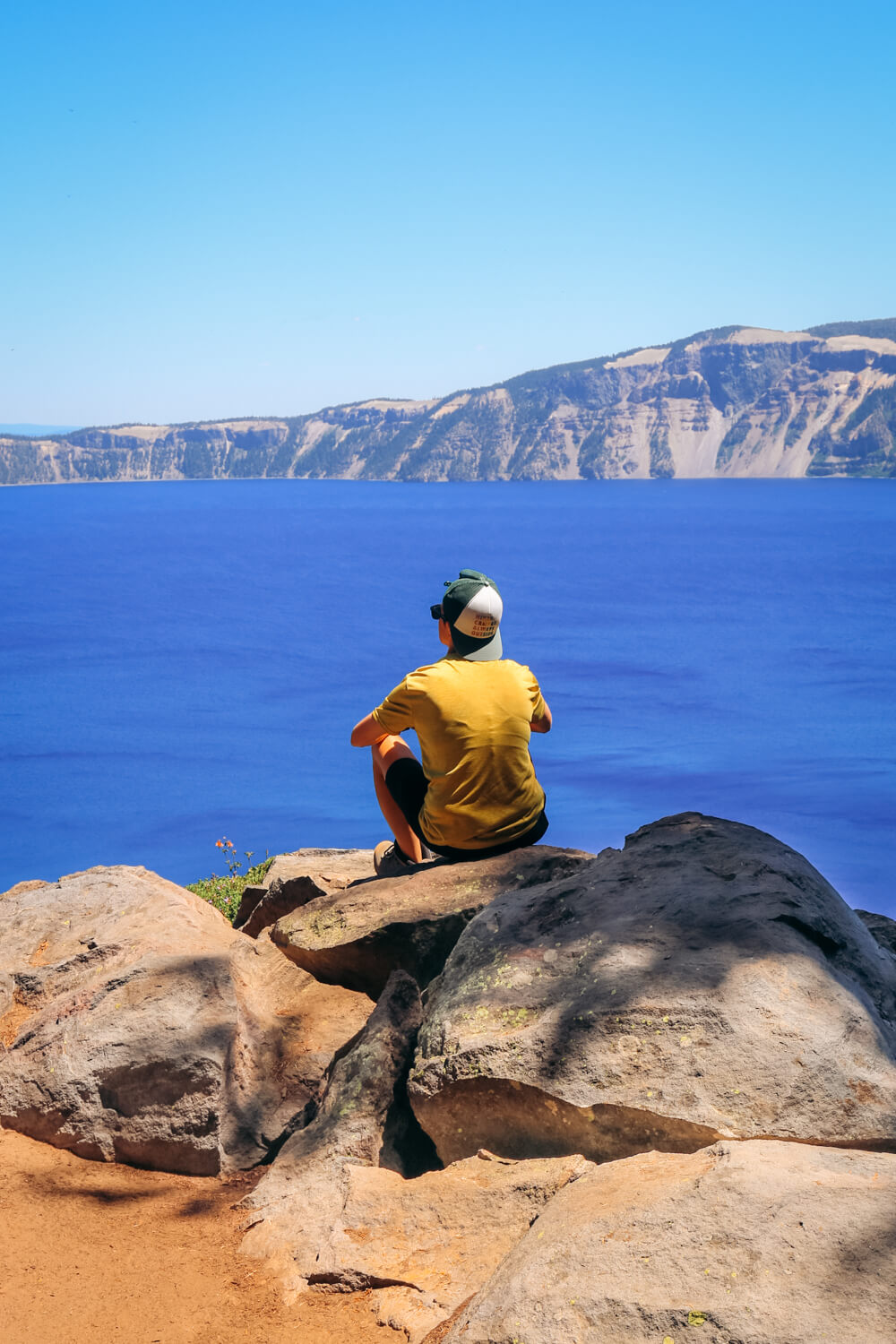 girl sitting on rock on crater lake rim trail