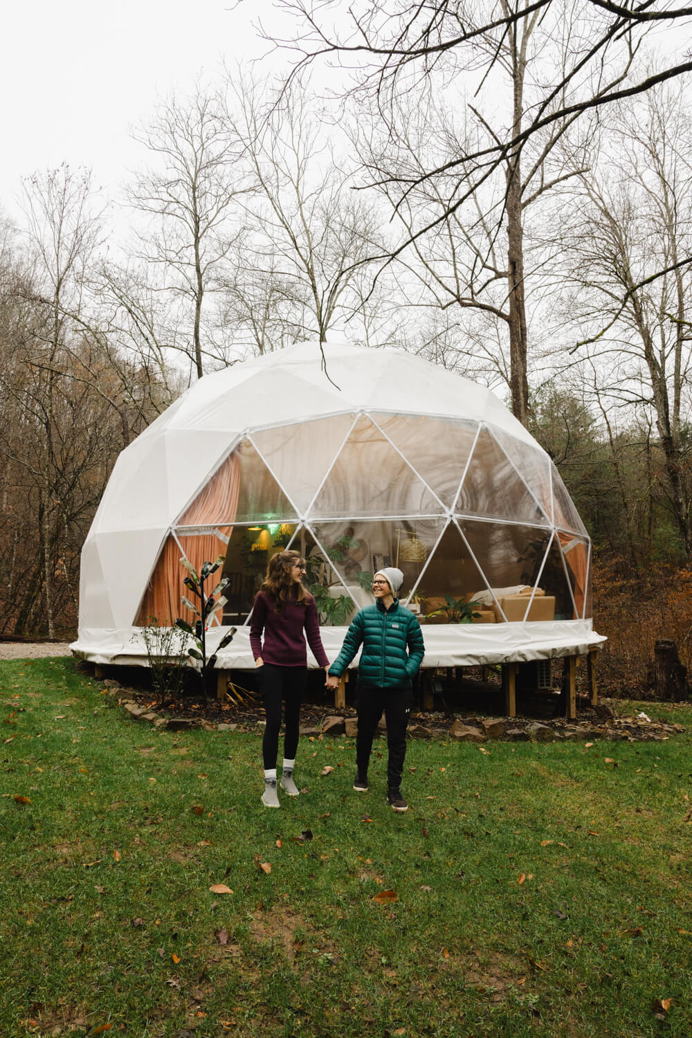 two girls walking and holding hands in front of glamping dome in madisonville tennessee in the winter