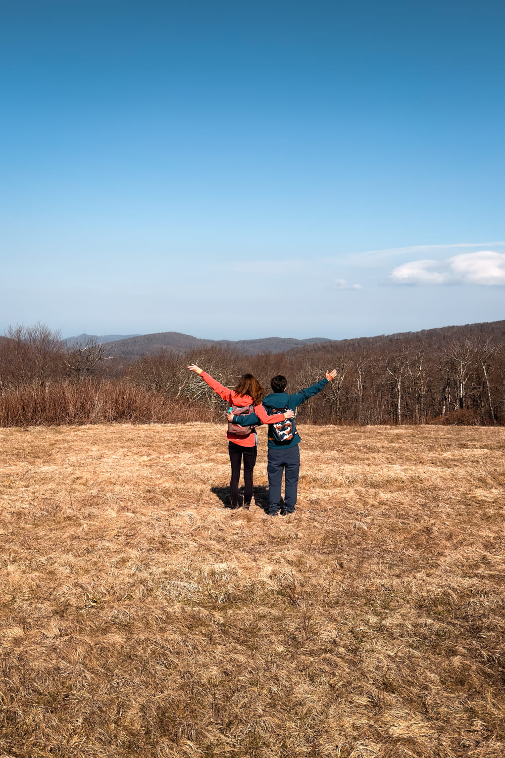 two hikers on hooper bald in the winter with their hands up
